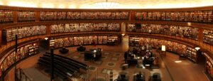 Panoramic view of a grand circular library with shelves full of books and study desks.